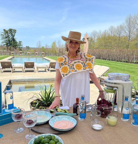 Martha Stewart in a hat behind a table with drinks