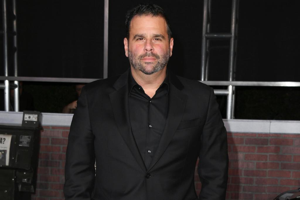 Randall Emmett posing on a red carpet in an all-black outfit.