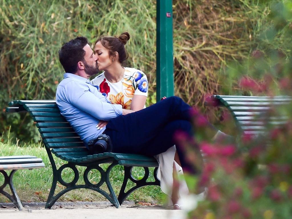 Ben Affleck and Jennifer Lopez kissing on a park bench.