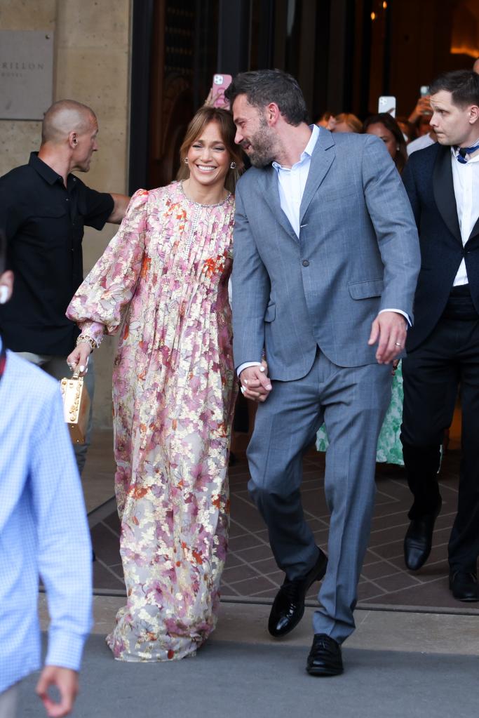 Jennifer Lopez and Ben Affleck smiling as they hold hands and walk through Paris