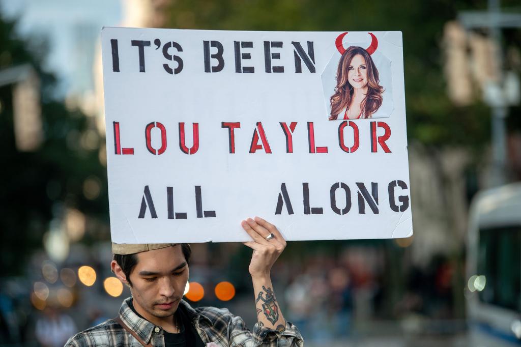 A Britney Spears fan holding a sign that reads, "It's been Lou Taylor all along."