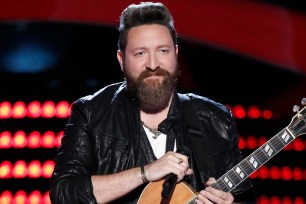 Nolan Neal holding his guitar onstage on "The Voice."