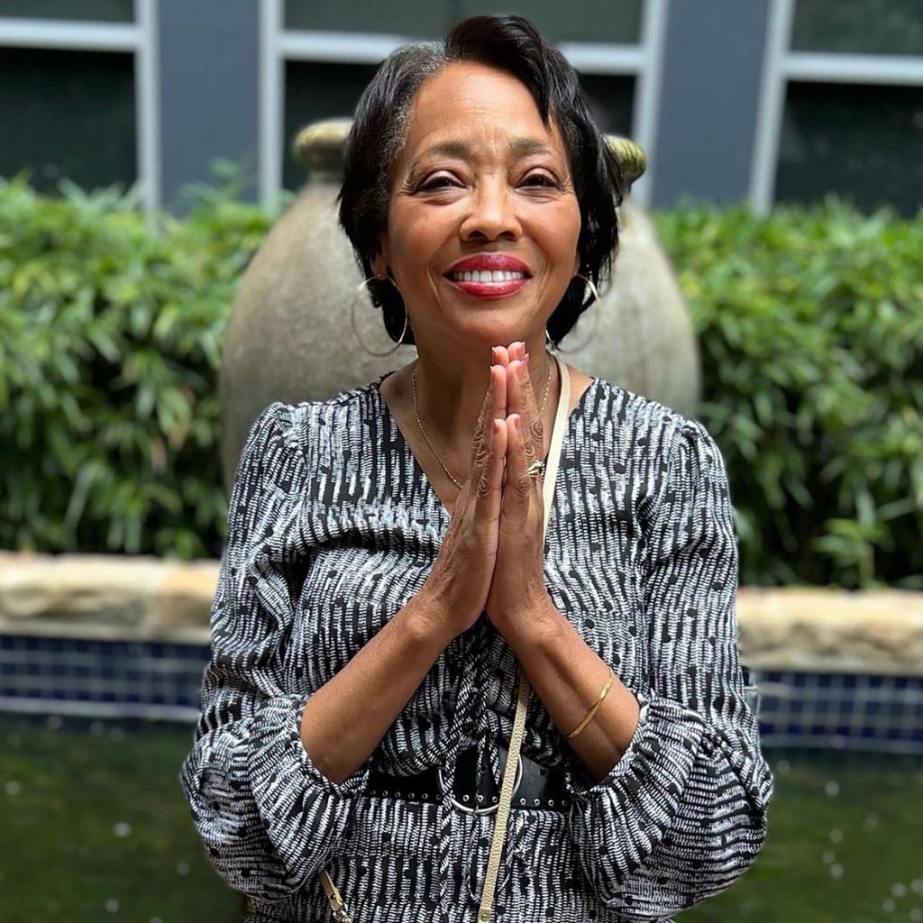 Barbara Ford Morris standing with her hands clasped in prayer.