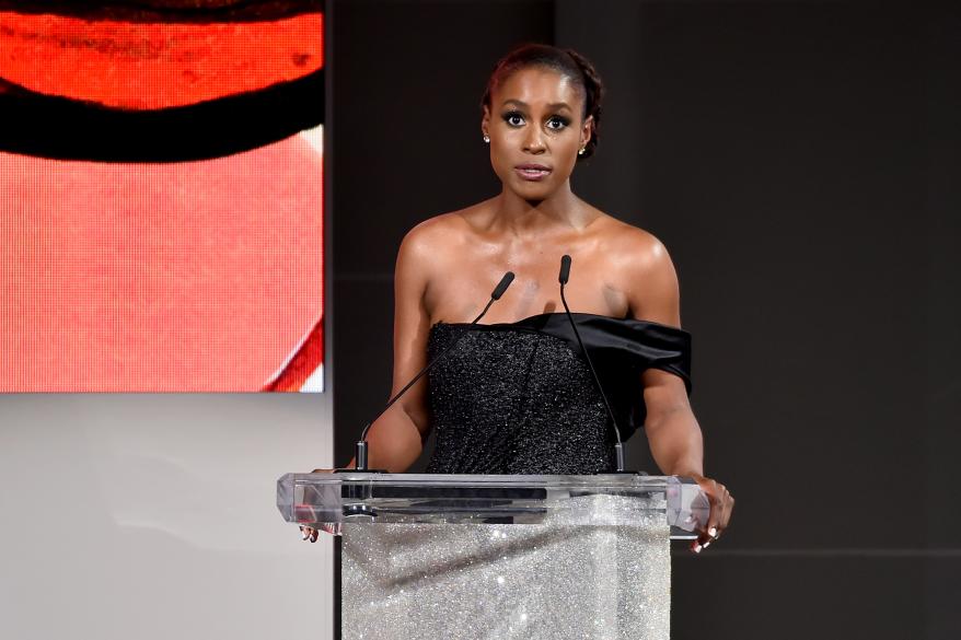 Issa Rae at a podium in a black dress