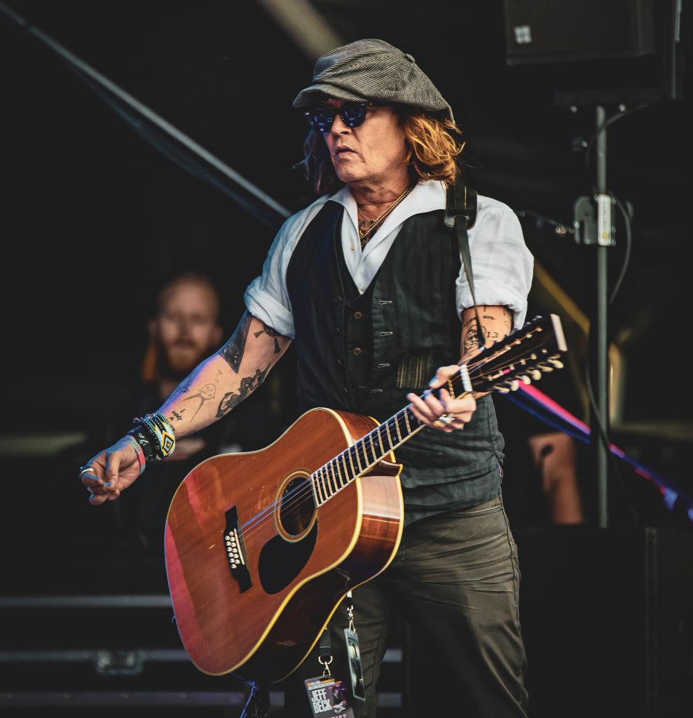 Johnny Depp playing a guitar on stage.