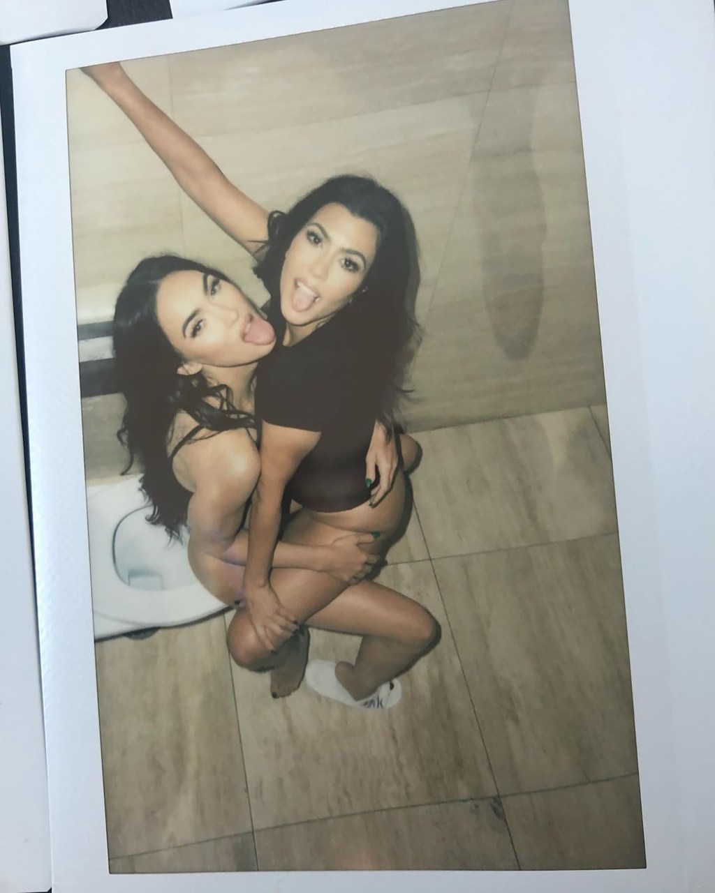 Kourtney Kardashian straddling Megan Fox on a toilet