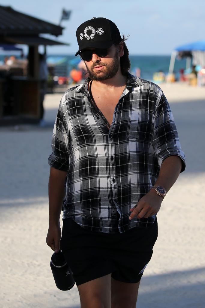 Scott Disick walking on a beach.