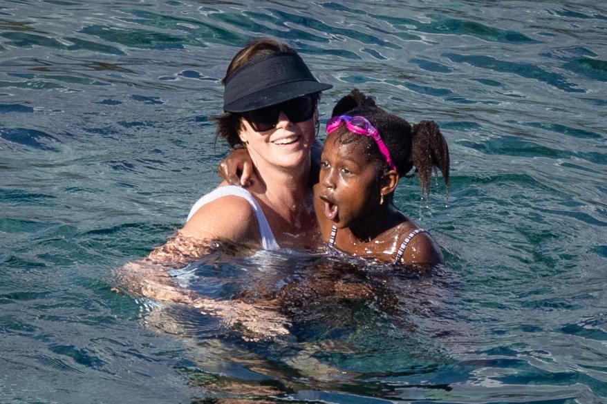 Charlize Theron holding one of her daughters in the water off the coast of Porto Ercole