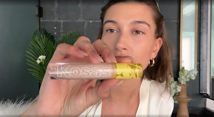 Hailey Bieber holding up a Kosas concealer