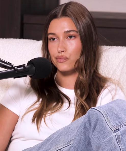 Hailey Bieber sitting in a chair making an annoyed face.