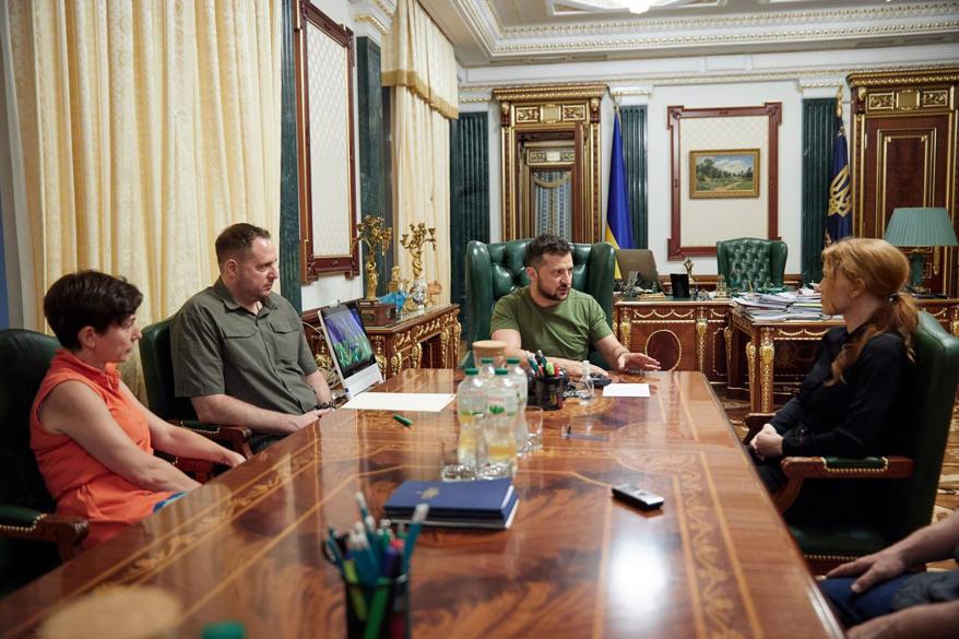 Ukraine President Volodymyr Zelensky at a conference table with colleagues and Jessica Chastain