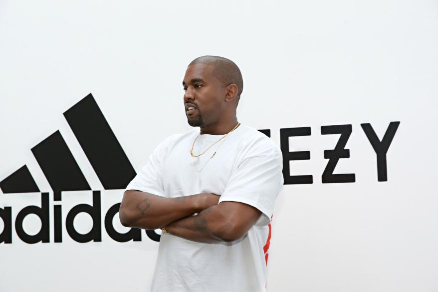 kanye west crossing his arms in front of adidas signage