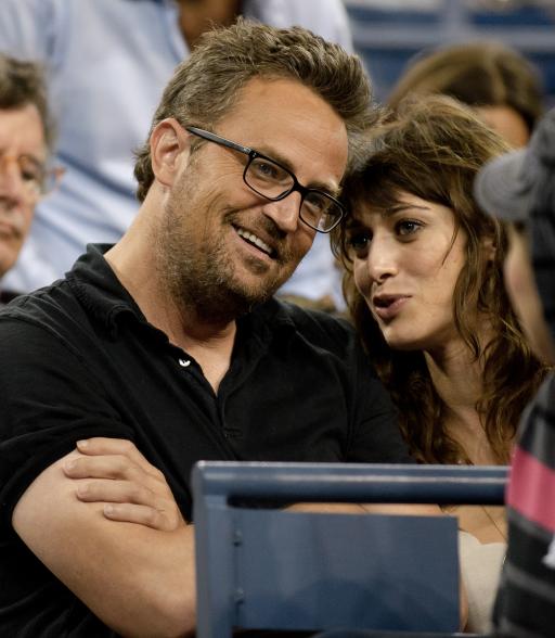 Matthew Perry and Lizzy Caplan talking at a sporting event.