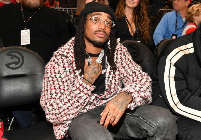 Quavo sitting down at a basketball game.