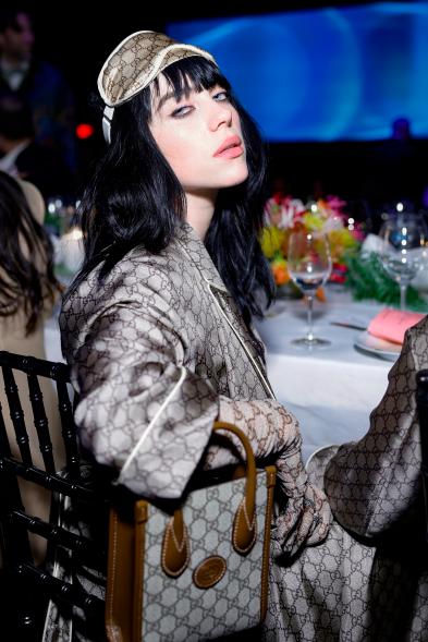 Billie Eilish sitting down at a table.