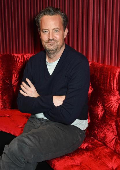 Matthew Perry sitting down with his arms crossed.