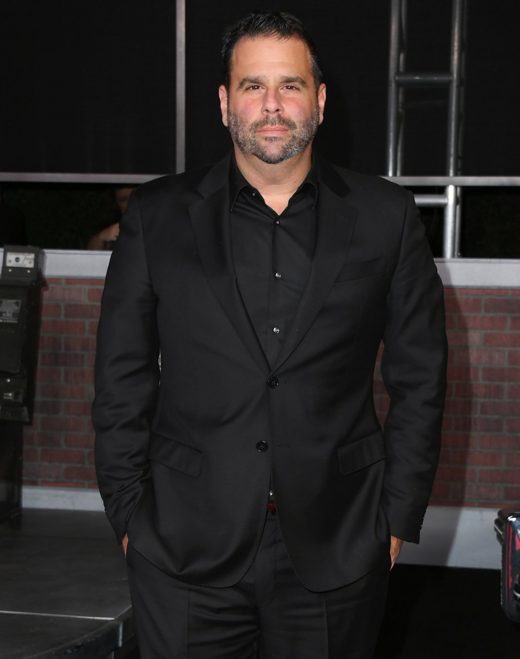 Randall Emmett standing in a black suit.