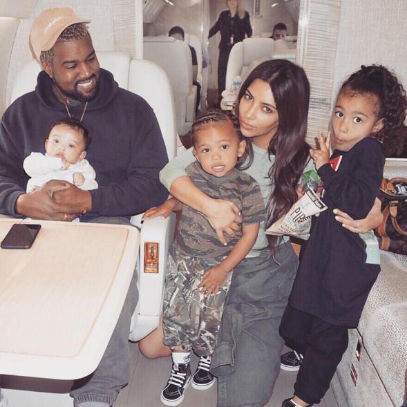 Kanye West and Kim Kardashian posing with their three kids