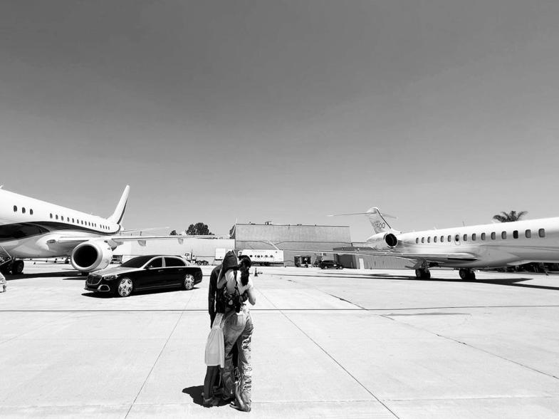 Kylie Jenner and Travis Scott kissing in front of a private plane.