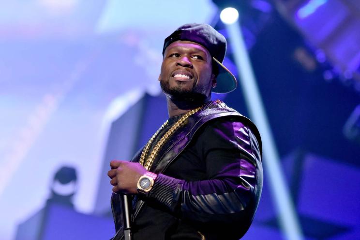 50 Cent holding a microphone on a stage.