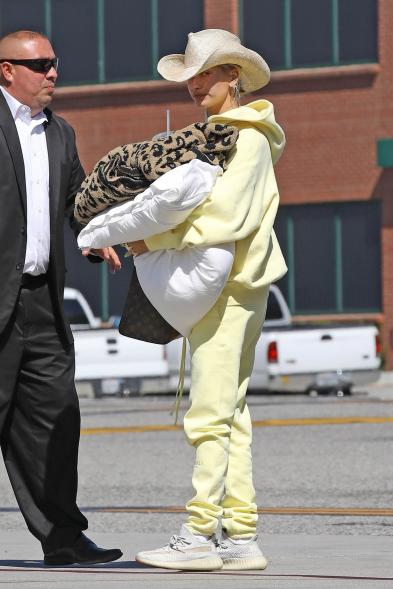 Hailey Bieber in a yellow tracksuit carrying a leopard-print blanket