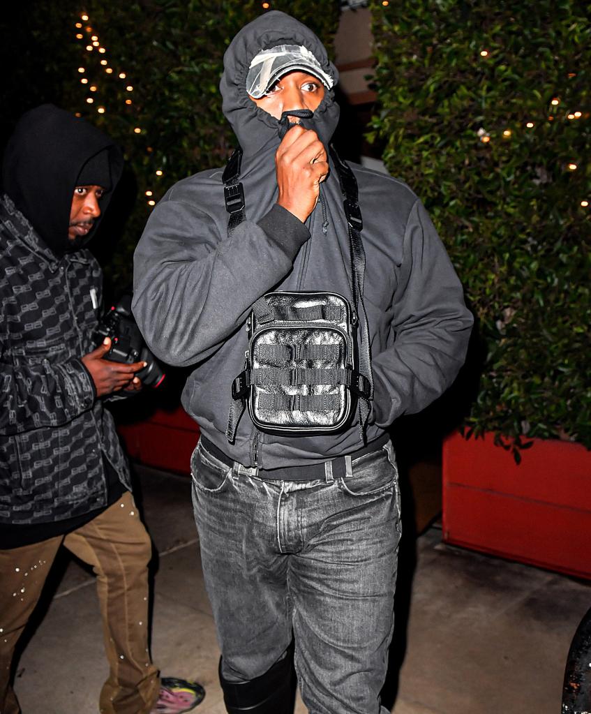 Kanye West wearing a black hoodie that covers most of his face.