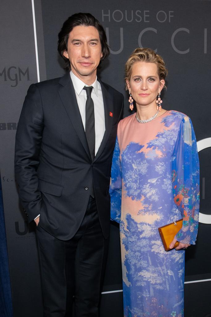 Suited Adam Driver poses beside Joanne Tucker on a red carpet