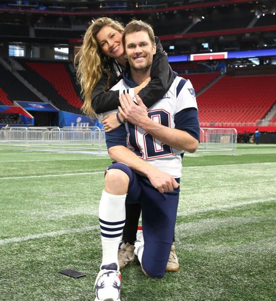 Tom Brady and Gisele Bündchen hugging on the football field.