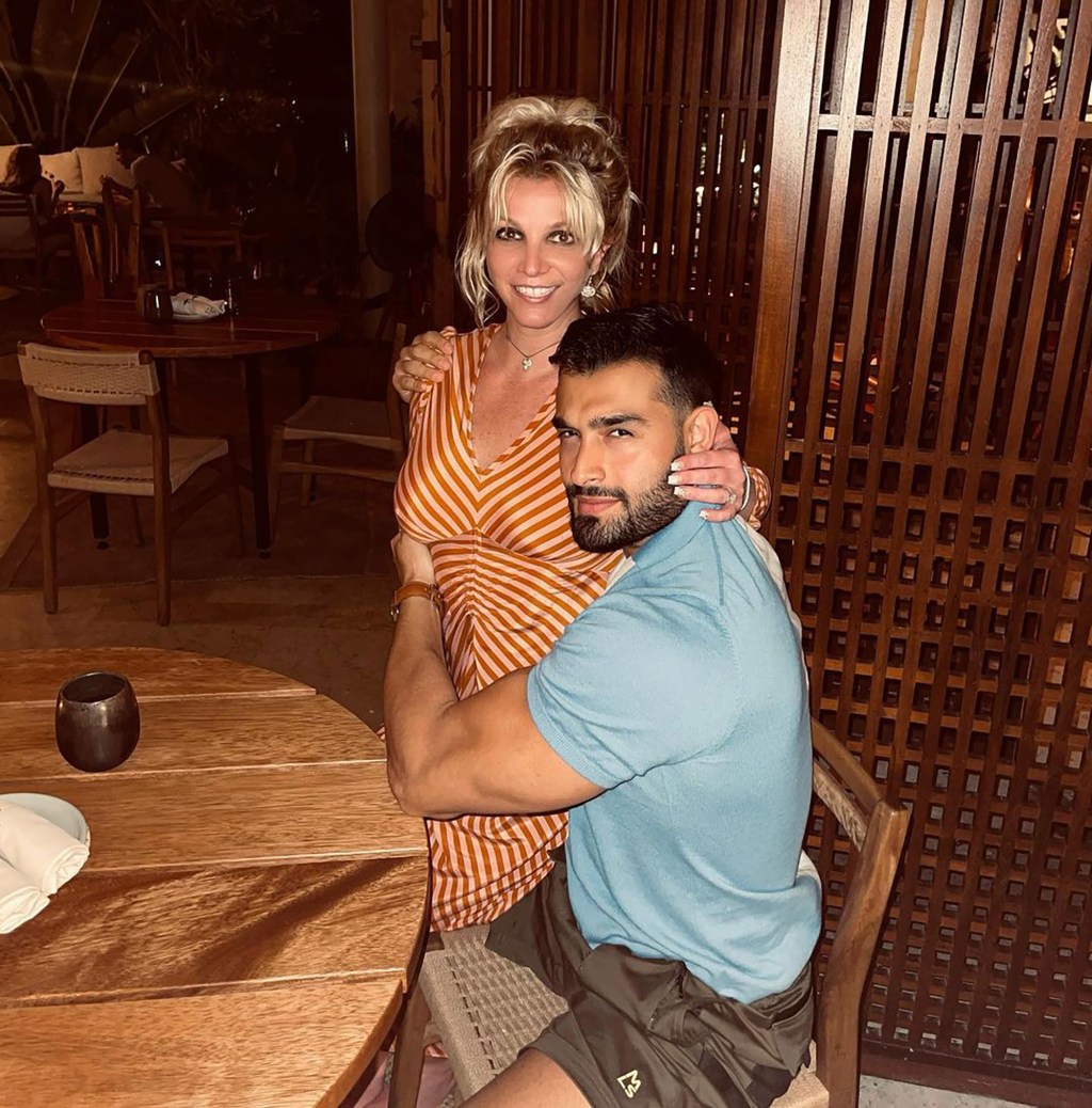 Sam Asghari and Britney Spears posing together in a restaurant.