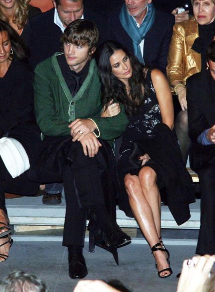 Ashton Kutcher sits beside Demi Moore in green sweater and black pants