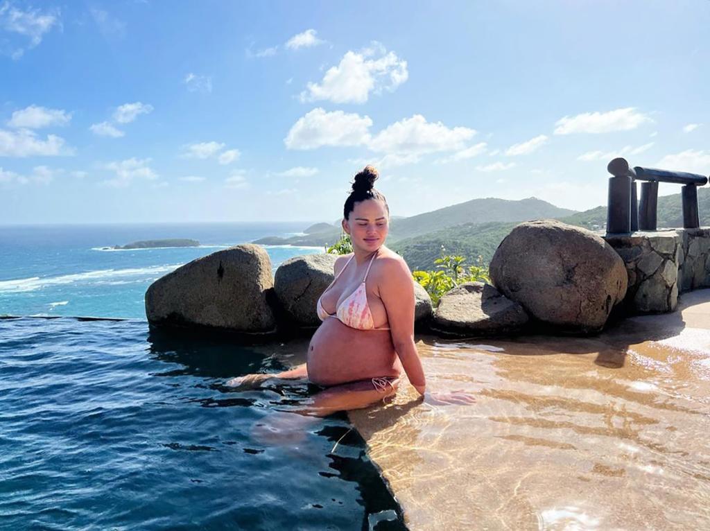 Pregnant Chrissy Teigen sitting in a pool.