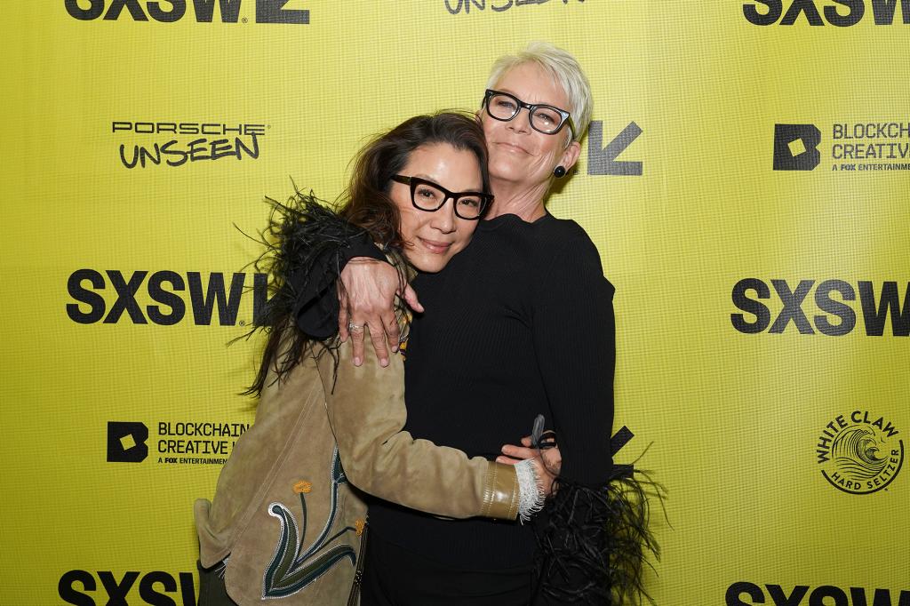 Jamie Lee Curtis and Michelle Yeoh hugging on a red carpet.