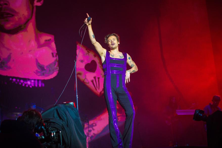 Harry Styles performs in a purple and black outfit