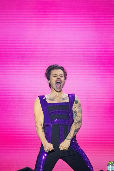 Harry Styles performs in a purple and black outfit