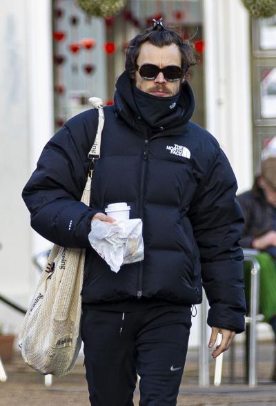 Harry Styles carries a coffee while bundled up