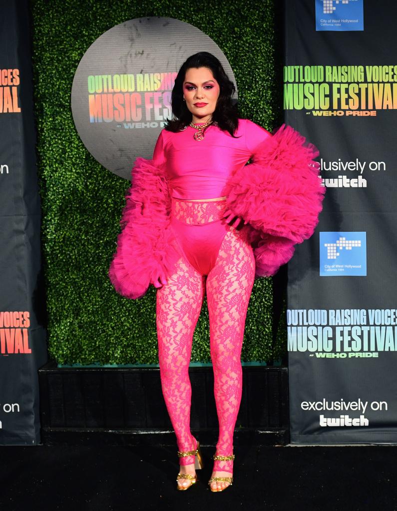 Jessie J puts one hand on her hip in a pink outfit