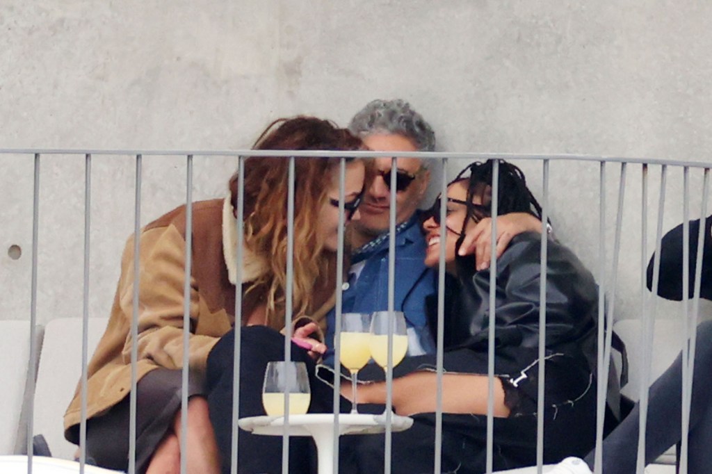 rita ora going in for a kiss with tessa thompson with taika waititi in the middle