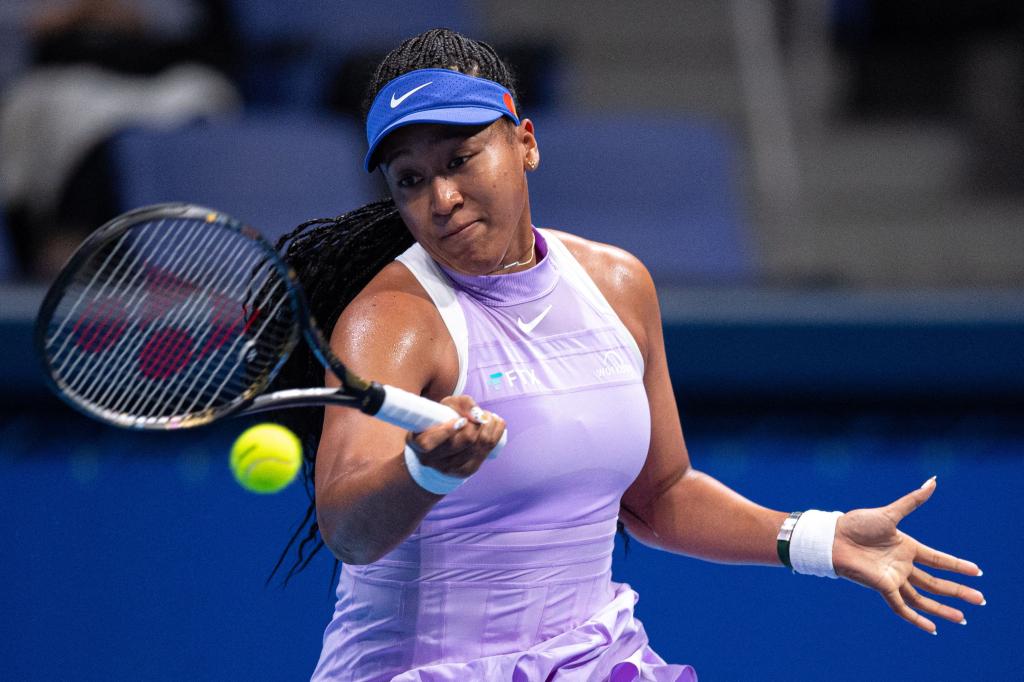 Naomi Osaka plays tennis in white top and blue visor