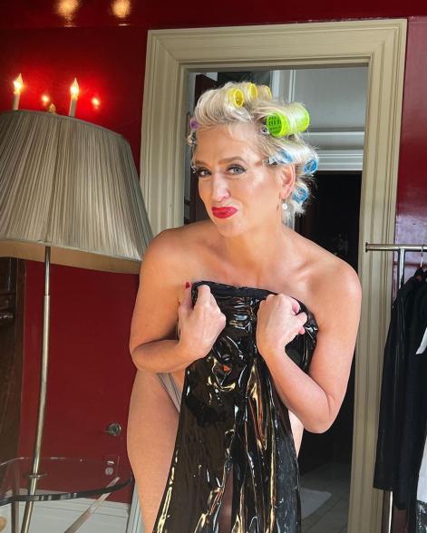 Dorinda Medley posing without a top on and holding a sparkly dress over her chest.