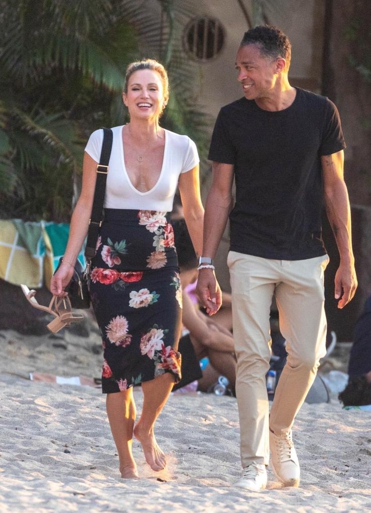 Amy Robach and T.J. Holmes walking together on a beach.