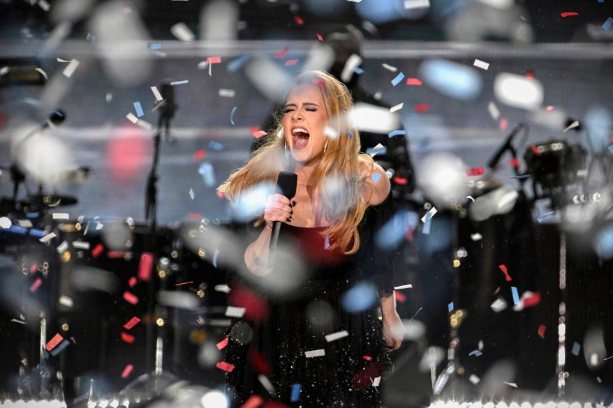 Adele singing onstage with confetti around her.