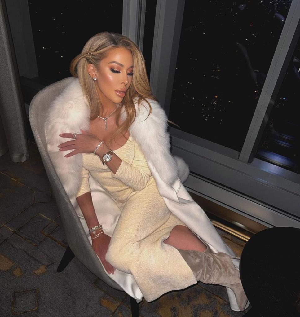 Lisa Hochstein posing on a chair with a fur jacket over her.
