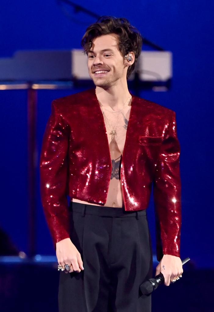 Harry Styles smiles in sequined red outfit while onstage