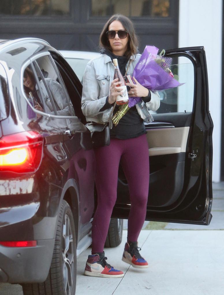 Kristen Doute outside of Ariana Madix's house holding flowers.