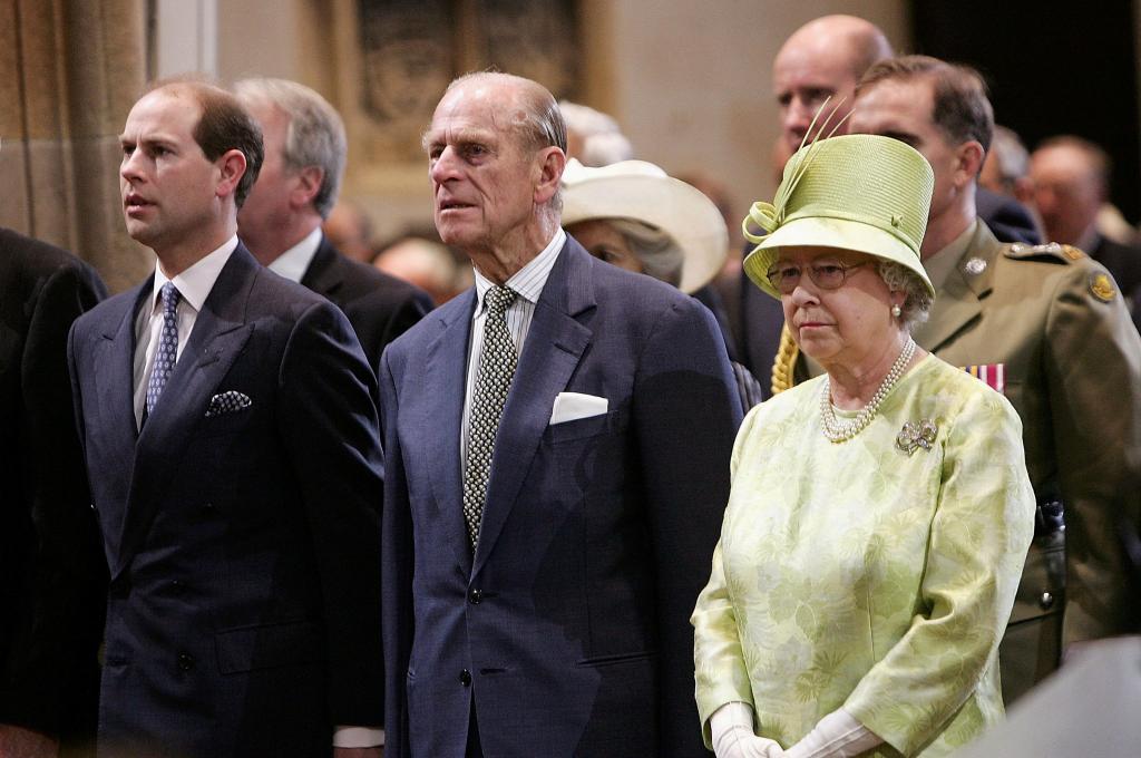 Prince Edward stands beside Prince Philip and Queen Elizabeth II in green