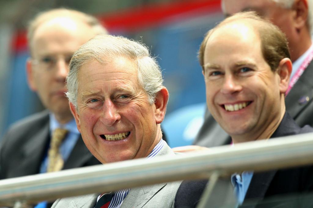 King Charles III smiles sitting beside Prince Edward
