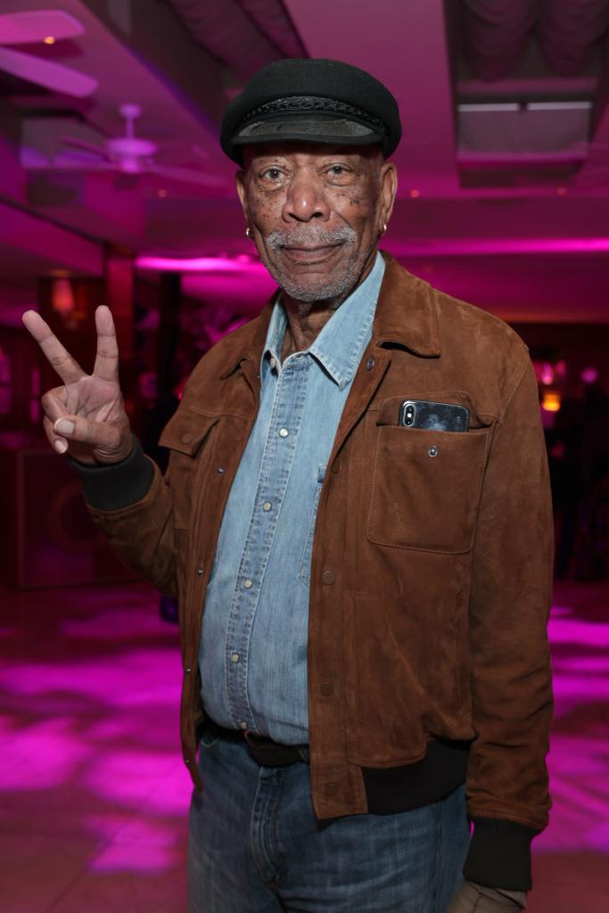 Morgan Freeman making a peace sign with his hand at an event.