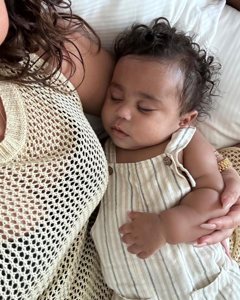 Adrienne Bailon in bed in white cuddling her baby boy.