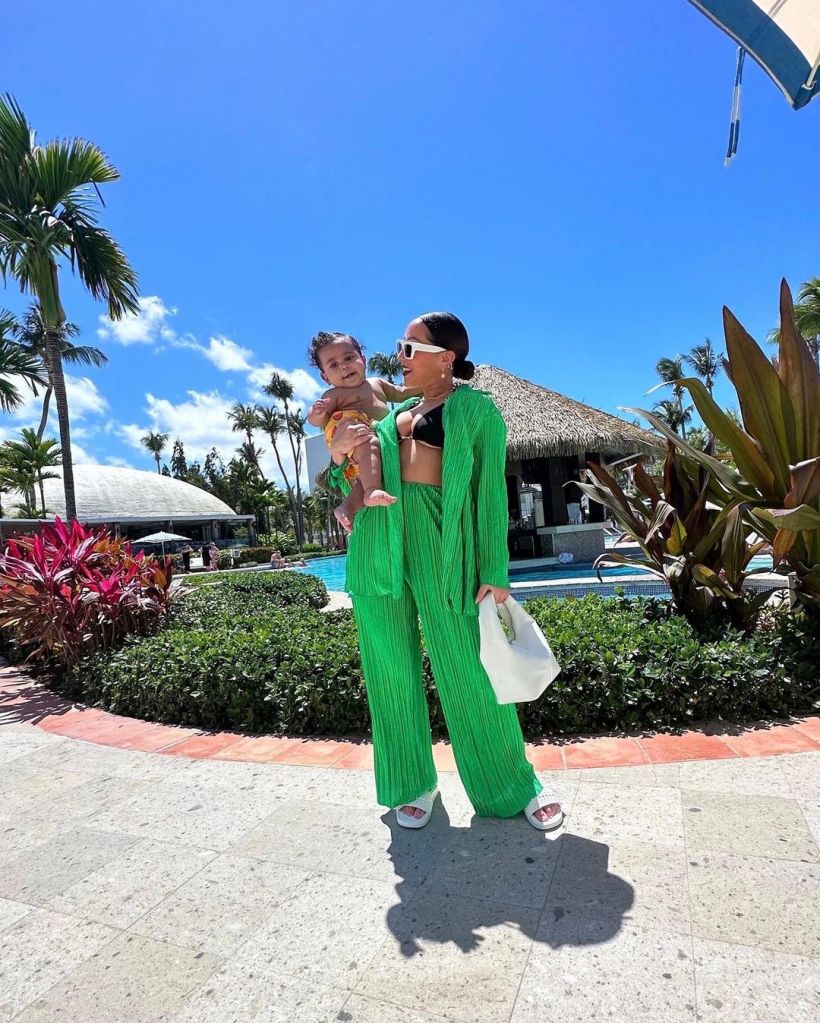 Adrienne Bailon in green suit standing outside with her son Ever James.