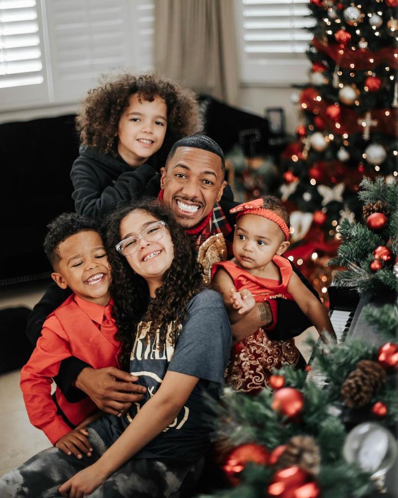 Nick Cannon with four of his kids in front of a Christmas tree.